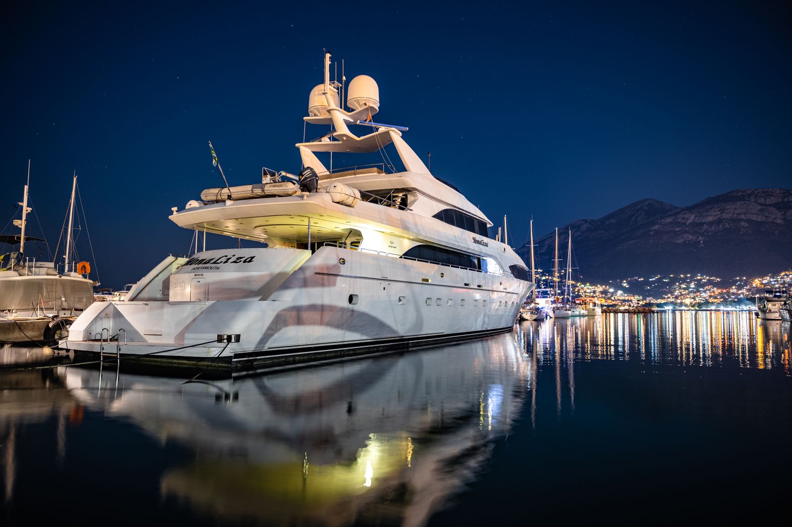 Yacht mirrored in marina water at night